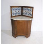 An Edwardian mahogany corner washstand, with marble top and William Morris style tiled back.