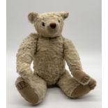A Steiff style teddy bear with glass eyes, plush fur, fully jointed limbs and stitched nose and claw