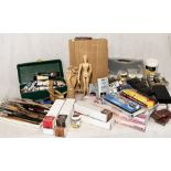 A large collection of art supplies including paints, paintbrushes, easel, wooden mannequin figures
