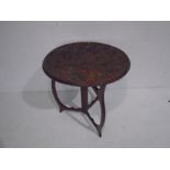 An African carved circular table on folding tripod base