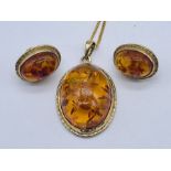 An amber pendant and matching earrings all set in 9ct gold