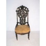 A Victorian nursing chair, with carved Black Forest style decoration to back - in need of