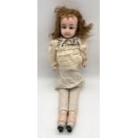An antique wax head and shoulder doll with elongated legs and painted feet