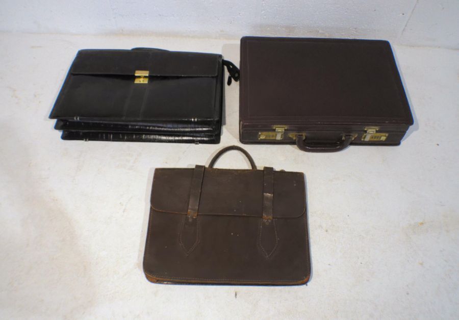 A leather briefcase along with two leather satchels.