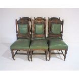 A set of six leather upholstered dining chairs with carved detailing to back.
