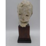 A painted bust of a child's head mounted on a plinth, overall height 36cm