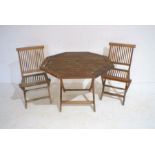 A weathered folding teak garden table with two chairs.