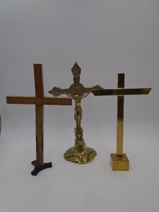 A vintage brass crucifix along with two crosses on stands, height of crucifix 33.5cm