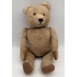 A vintage teddy bear with jointed legs and elongated nose