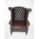 A Thomas Lloyd leather wingback chair, with button-back detailing.