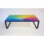 A modern metal framed coffee table with multi-coloured top.