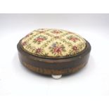 An inlaid upholstered footstool with ceramic feet.