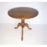 A mahogany low tip-up table on tripod base.