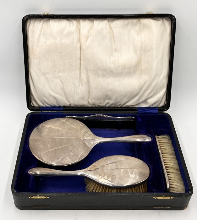 A cased hallmarked silver (Birmingham 1921) Art Deco dressing table set consisting of mirror, two