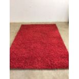 A large red rug hand tufted with thick and thin yarns, made by Veronica. Pile is 100% Polyester W: