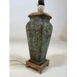 A heavy bronzed Eastern lamp base with geometric decorations on wooden base with wooden lid. H:27cm