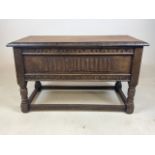 A small oak coffer on raised legs with carved detail.
