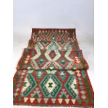 A Chobi Kilim runner with orange ground and green and turquoise pattern W:88cm x H:302cm