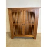 A modern teak shoe cupboard purchased in the Far East with slatted front and interior shelves. W: