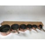 A set of 6 vintage copper pans with a wooden rack ( 79cm width) W:16cm x H:8cm dimensions of the