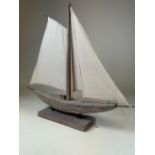 A Model of a pond yacht with canvas sails on wooden stand. H:58cm