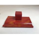 An orange Bakelite ink stand with glass ink well. 2 black feet missing - see photo W:19.5cm x D:13cm