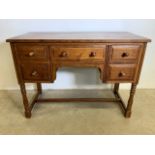 A solid oak small knee hole desk with central drawer flanked by two drawers with turned rustic