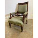 An early 20th century upholstered arm chair with turned legs and brass and ceramic castors. W:70cm x