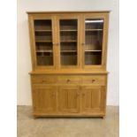 A modern solid oak two piece glazed display bookcase with sideboard to base. Three glazed doors to
