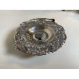 A Eastern white metal bon bon dish with carry handle. Decorated with wildlife.