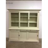 A large modern housekeepers cupboard, three glazed sliding doors to top with interior shelves,