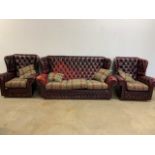 An Oxblood red wing back sofa and two chairs with button back and studded finish. (A.F) SOFA W:186cm