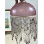 A pink frosted lamp shade with beaded decoration together with a brass shade with beaded