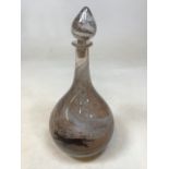 An art glass decanter with mottled design of cats running around the base. Chip to inside of stopper