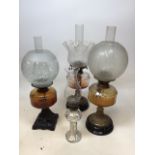 Three oil lamps with decorative glass shades, one with cast iron decorative base, two with brass