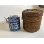 A chinese blue and white tea pot in rattan basket.