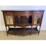 An ornate mirrored sideboard with central bow fronted galleried shelves flanked by cupboards and