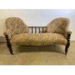 A double backed victorian sofa with turned barley twist legs and serpentine front on brass