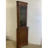 An inlaid Edwardian two piece corner cupboard with glazed top to lined shelves, Base with