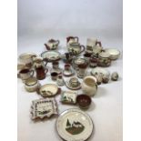A quantity of Torquay Mottoware includes, plates, jugs, mugs, cups, candle stick, egg cups, Sussex
