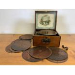 A Monopol music box with thirteen (13) music discs. In working condition with winder. W:29cm x D: