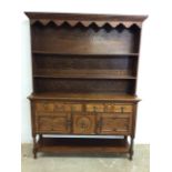 A two piece oak dresser with two plate rack above base with two drawers above cupboards, bottle