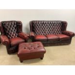 A red leather wing and button back cheserfield style three seater sofa and arm chair with later foot