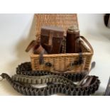 A wicker picnic basket with leather flasks and leather and canvas bullet belts.