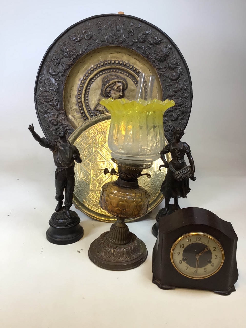 Brass chargers, an oil lamp, a pair of spelter figures and a Smiths Bakelite clock