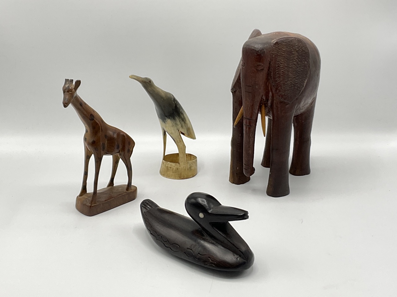 An East African polished hardwood bull elephant, an ebony duck, a hardwood giraffe and a horn bird