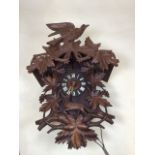 A large imposing black Forrest style wooden cuckoo clock. Ornately carved with vines, bird and a