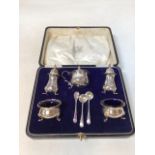 A boxed hallmarked silver cruet set with glass lined salts - one later replacement. Total weight
