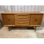 A Mid century teak sideboard with four central drawers flanked by cupboards with square handles