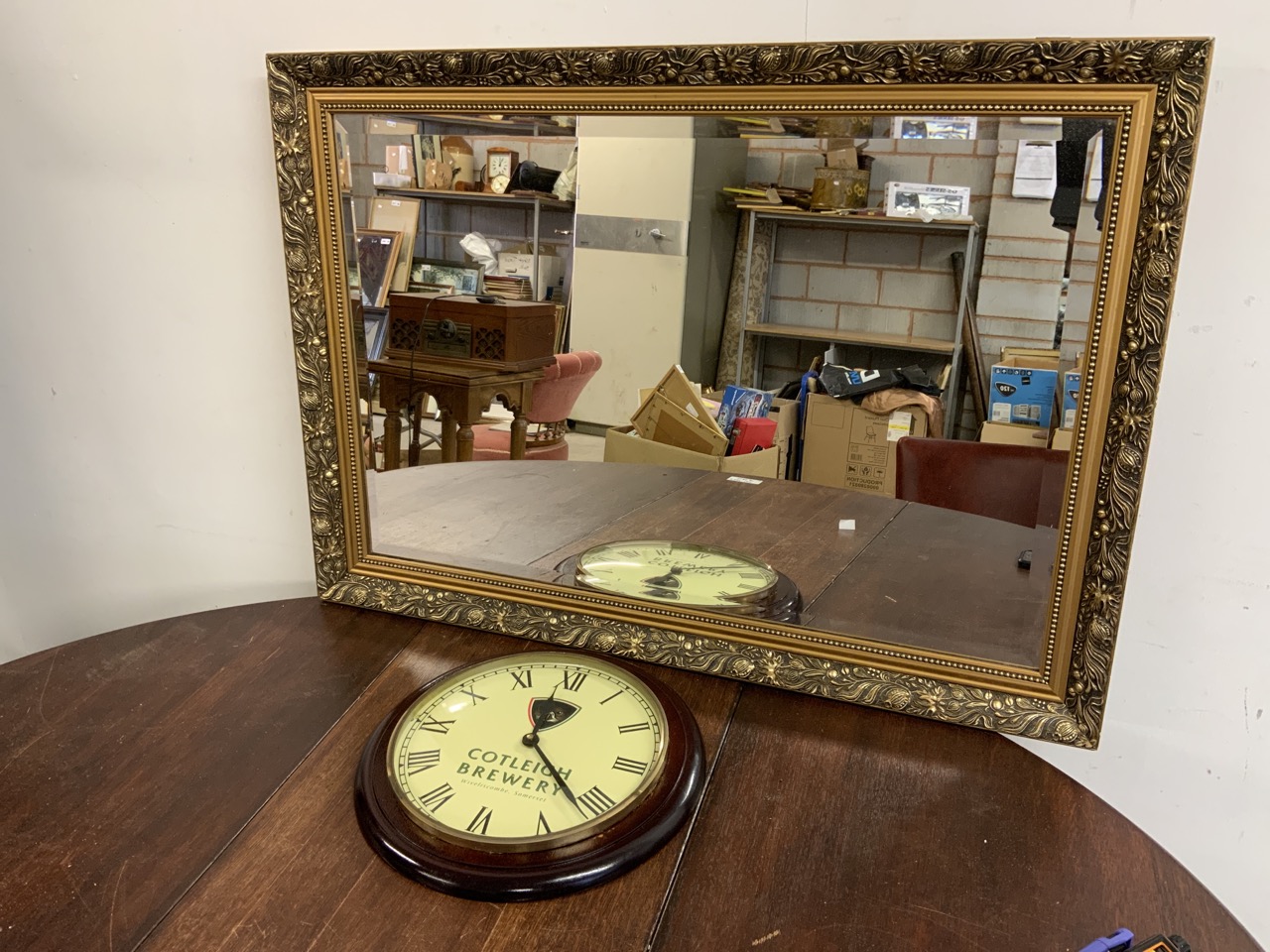 A Cotleigh Brewery circular clock also with a gilt framed bevelled mirror. W:87cm x H:61cm